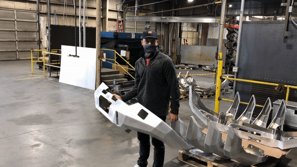 Man lifting a Backwoods Adventure Mods 3rd Gen Toyota Tacoma (2016-2023) Hi-Lite hybrid aluminum Off Road high clearance Front Bumper with one hand demonstrating it's light weight and ease of install